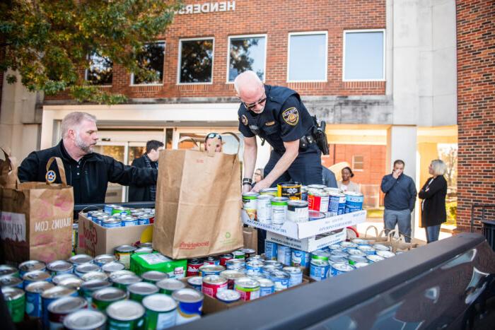 Officers helping load truck with food cans for donations.